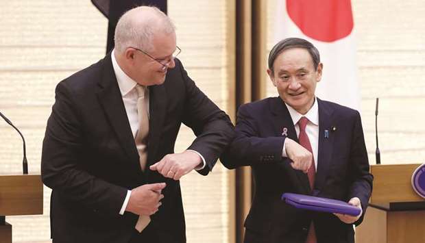 Yoshihide Suga, Japanu2019s prime minister bumps elbows with Scott Morrison, Australiau2019s prime minister, after receiving the medals of the 2000 Sydney Summer Olympic Games from him, during a joint news conference at Sugau2019s official residence in Tokyo, Japan.