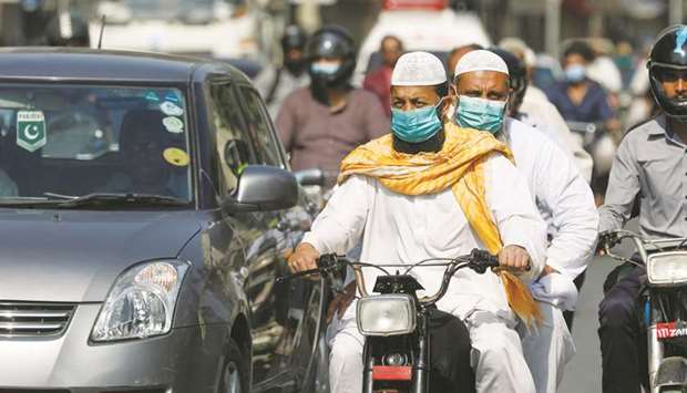 Men wear protective masks as they ride a motorcycle amid the outbreak of the coronavirus disease in Karachi.