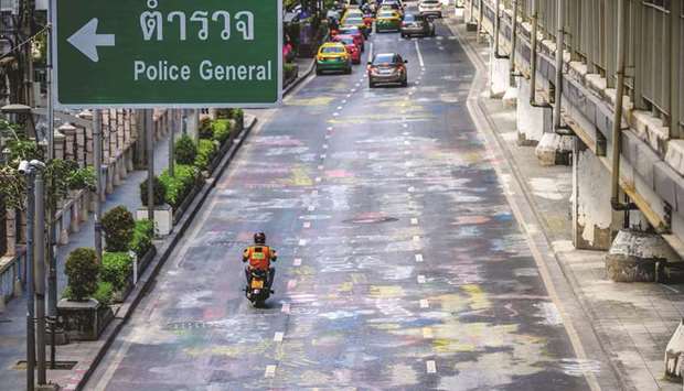 A motorist drives on the street in front of the Royal Thai Police Headquarters covered with graffiti in the aftermath of a pro-democracy demonstration in Bangkok yesterday.