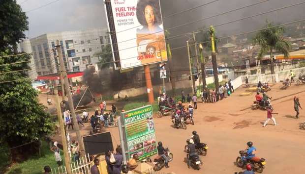 People ride motorcycles as smoke rises from burning objects in a street in Kampala, Uganda November 18 in this screen grab obtained by Reuters from a social media video on November 20.