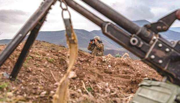 An Armenian soldier looks through binoculars during a patrol yesterday at the checkpoint nearby a demarcation line outside Askeran, as Azerbaijani troops moved the day before into the Aghdam district bordering Nagorno-Karabakh.
