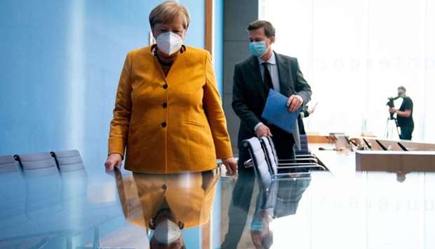 German Chancellor Angela Merkel (L) and German government spokesman Steffen Seibert leave after a press conference on the current situation amid the novel coronavirus pandemic, following a meeting with her so-called Corona-Cabinet in Berlin.