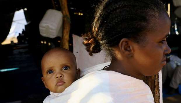 An Ethiopian woman who fled war in Tigray region carries a child on her back as she walks at the Um-Rakoba camp on the Sudan-Ethiopia border in Al-Qadarif state, Sudan November 19.