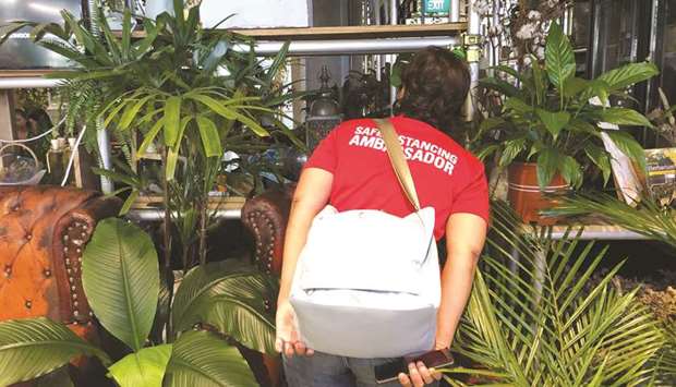VIGILANT: Public servant Rugayah Noordin peers between plants into a restaurant to ensure diners are spaced apart.