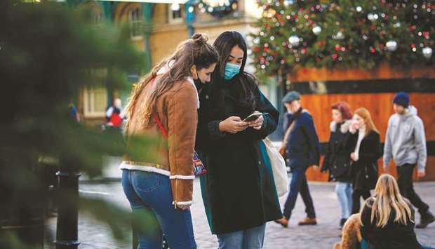 Pedestrians wearing protective face covering to combat the spread of the coronavirus, look at a phone in Covent Garden in central London, yesterday.