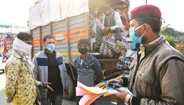 A Delhi Civil Defence (DCD) volunteer fines a truck owner for not maintaining social distancing in transporting people as a preventive measure against the coronavirus, in New Delhi yesterday.