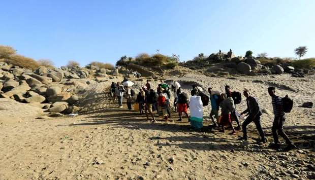 Ethiopians who fled the ongoing fighting in Tigray region, carry their belongings from a boat after crossing the Setit river on the Sudan-Ethiopia border in Hamdayet village in eastern Kassala state, Sudan
