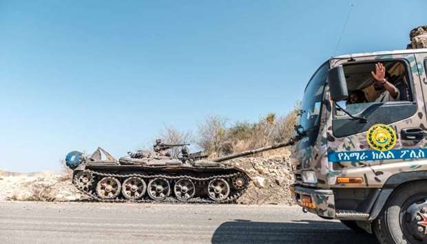 A damaged tank stands abandoned on a road as a truck of the Amhara Special Forces passes by near Humera, Ethiopia, on November 22.