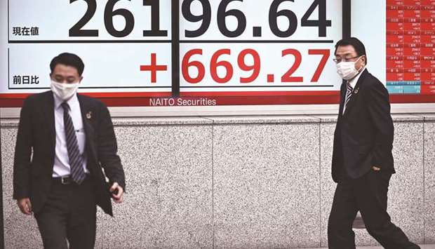 Pedestrians walk past an electronic quotation board displaying share prices in Tokyo. The Nikkei 225 closed up 2.6% to 26,196.64 points on Tuesday.