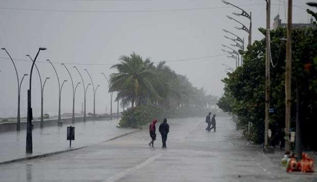 Policemen walk along a deserted beach road during heavy rains as cyclone Nivar approaches the southeastern Indian coast in Puducherry