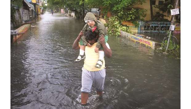 A man carries a child through a water-logged road after cyclone Nivaru2019s landfall, in Chennai yesterday.