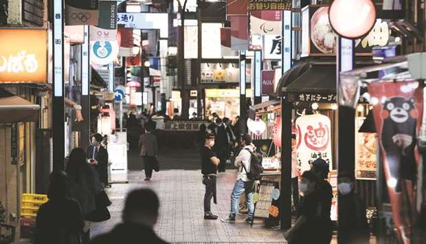 Pedestrians walk past restaurants at night in the Shinjuku district of Tokyo. As coronavirus infections in Japan spark increasing alarm, the government has left investors guessing on how much money it will pump into the economy through a third extra budget.