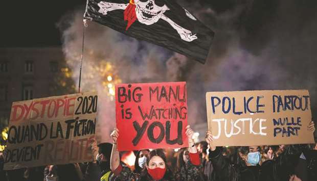 This picture taken on Thursday night shows protesters holding placards reading (from left) u2018Dystopia 2020 when fiction becomes realityu2019, u2018Big Manu (referring to French President Emmanuel Macron)u2019, and u2018Police everywhere, justice nowhereu2019, as they take part in a demonstration in Toulouse, against the u2018global securityu2019 draft law, which seeks to limit filming and photographing police officers on duty.