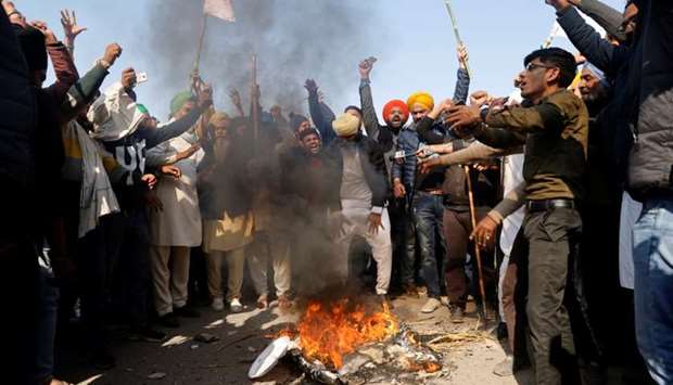 Farmers shout slogans as they burn an effigy during a protest against the newly passed farm bills at Singhu border near Delhi, India