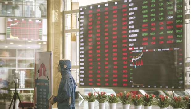 A worker wearing a protective suit stands at a temperature screening point in front of an electronic stock board at the Shanghai Stock Exchange. The Composite closed up 1.4% to 3,271.07 points yesterday.