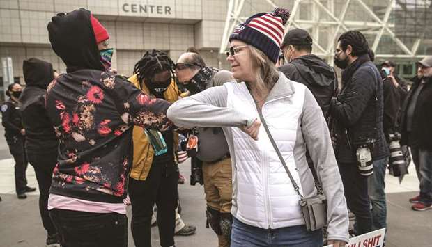 A Trump supporter and an anti-Trump protester bump elbows yesterday in Detroit.