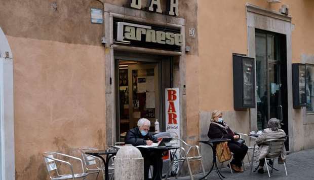People wearing protective masks, sitting at the coffee tables of a bar nera Piazza Farnese during the government restriction measures to curb the spread of Covid-19, in central Rome