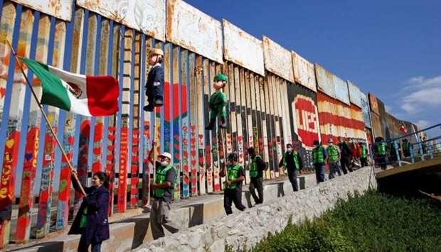Migrants and members of civil society hold pinatas in the image of Donald Trump and a border patrol officer during a protest against stalled asylum claims and the building of the wall, at the border fence between Mexico and the US in Tijuana, Mexico October 31, 2020