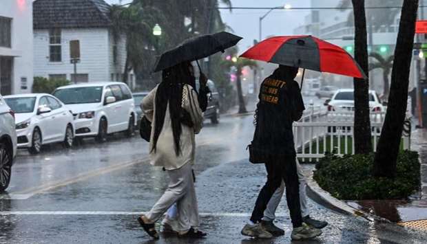People cross the street during a heavy rain and wind as tropical storm Eta approaches south of Florida, in Miami, Florida