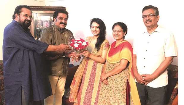 K K Sudhakaran and Mohan Ayroor presenting a bouquet to Nithya Mammen as her parents look on.