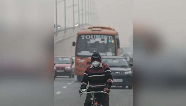 A cyclist makes his way along a road under heavy smog in New Delhi.
