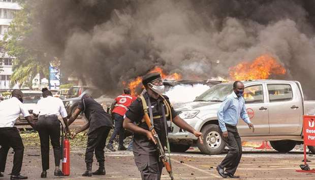 People extinguish fire on cars caused by a bomb explosion near Parliament building in Kampala, yesterday.