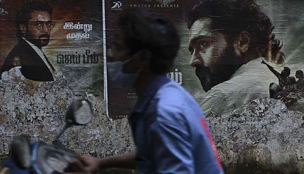 A motorist rides past a poster of actor Suriya Sivakumar from the movie Jai Bhim in Chennai on November 17, 2021.