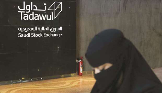 A Saudi woman walks at the Saudi Stock Exchange (Tadawul) in Riyadh. The bourse, on which oil giant Saudi Aramco trades, plans to sell a 30% stake, or 36mn shares.