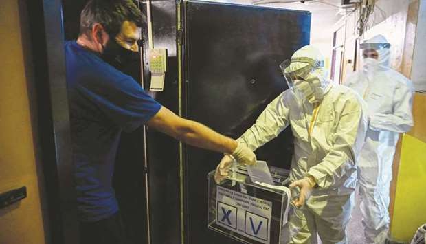 An electoral staff member of a mobile polling centre, wearing Personal Protective Equipment, presents a ballot box to a man in self-quarantine to collect his vote for the second-round of the presidential election and the parliamentary elections in Sofia yesterday. (AFP)