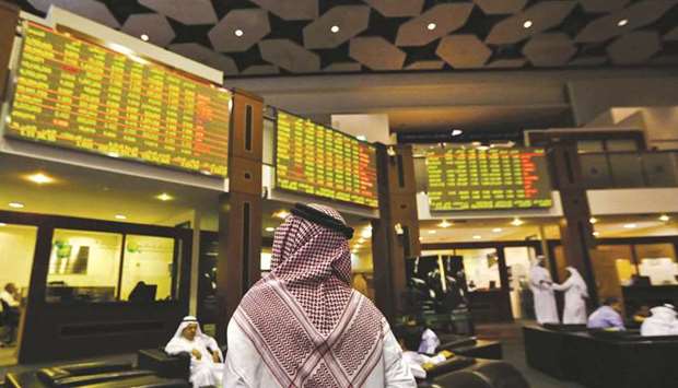 An investor looks up at screens displaying stock information at the Dubai Financial Market (file). The DFM has suffered a slide in trading, with volumes falling in three of the past four years, as a string of companies delisted at a time of declining liquidity and stock prices, while the Covid-19 pandemic has hurt the cityu2019s lifeblood tourism and real estate industries.