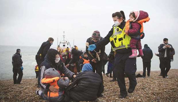 A member of the UK Border Force helps child migrants on a beach in Dungeness, on the south-east coast of England, yesterday after being rescued while crossing the  English Channel.