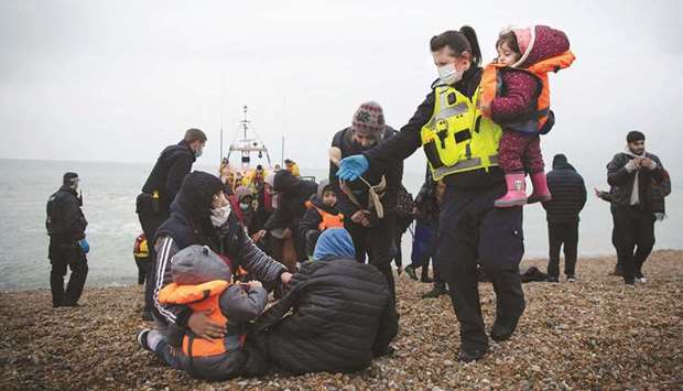 A member of the UK Border Force helps child migrants on a beach in Dungeness, on the south-east coast of England, yesterday after being rescued while crossing the English Channel.