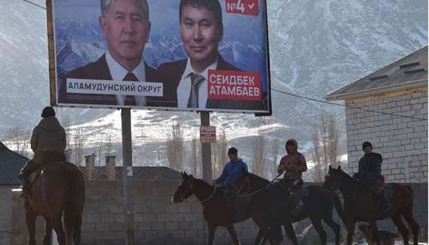 Men ride horses near a campaign billboard of Seitbek Atambayev, the son of ex-president Almazbek Atambayev and a candidate in the upcoming parliamentary election, in the village of Koy-Tash, some 25km from Bishkek yesterday