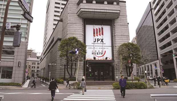 Pedestrians walk by the Tokyo Stock Exchange building. The Nikkei 225 closed down 2.5% to 28,751.62 points yesterday.
