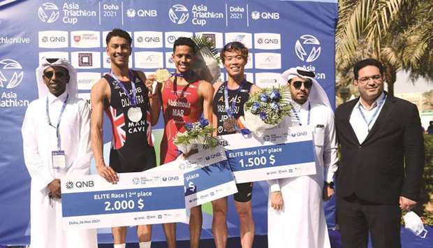 QTF president Dr Mohamed al-Kuwari (second right), QTF Secretary-General Thani al-Zarraa (left) pose with winners of the menu2019s elite race of the QNB Asia Triathlon Cup Doha 2021 at Lusail Marina on Friday.