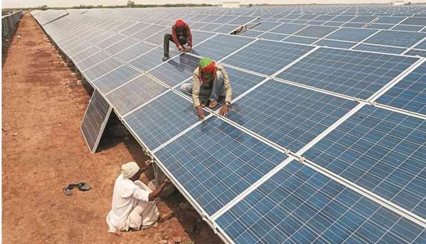 Going green: Indian workers are seen giving the finishing touches to solar panels in Gujarat. The country plans to ramp up renewable generation capacity almost fivefold to 450GW by 2030.  (AFP)