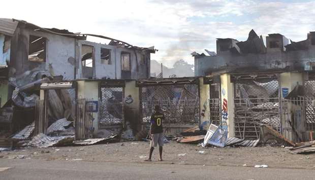 A man looks at damages in Honiara yesterday as a tense calm returned after days of intense rioting that left at least three dead and reduced swathes of the city to smouldering ruins.