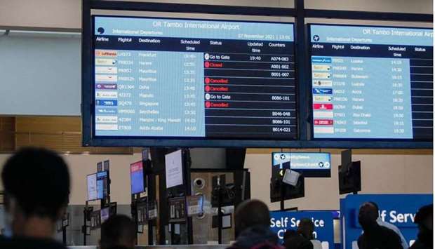 Travellers walk near an electronic flight notice board displaying cancelled flights at OR Tambo International Airport in Johannesburg yesterday, after several countries banned flights from South Africa following the discovery of a new Covid-19 variant Omicron