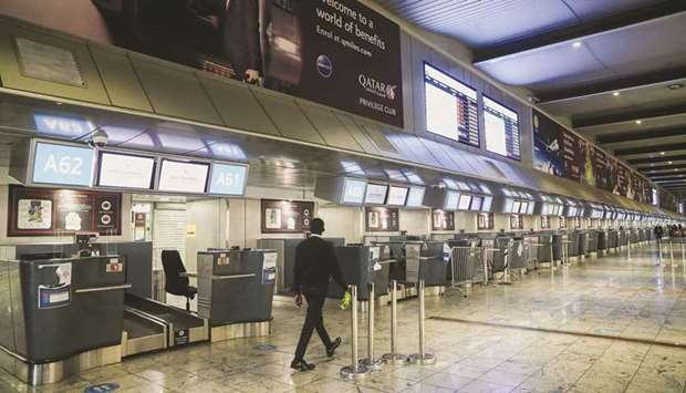 International check-in counters stand empty as several airlines stopped flying out of South Africa amid the spread of Omicron at OR Tambo International Airport in Johannesburg, South Africa, where (right) a passenger tries to find a flight yesterday. (Reuters)