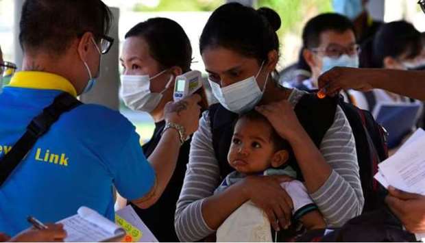 A mother and child get their temperatures checked as they prepare to board a bus back to Malaysia, as the Vaccinated Travel Lane between Singapore and Malaysia opens after the land border between the two countries reopened nearly two years of being shut down due to the coronavirus disease (Covid-19) pandemic, at a bus station in Singapore November 29, 2021.