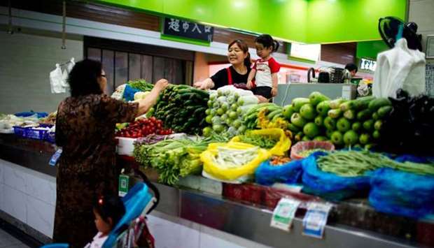 Two grandmothers with their granddaughter trade vegetables at a market on the outskirts of Shanghai.