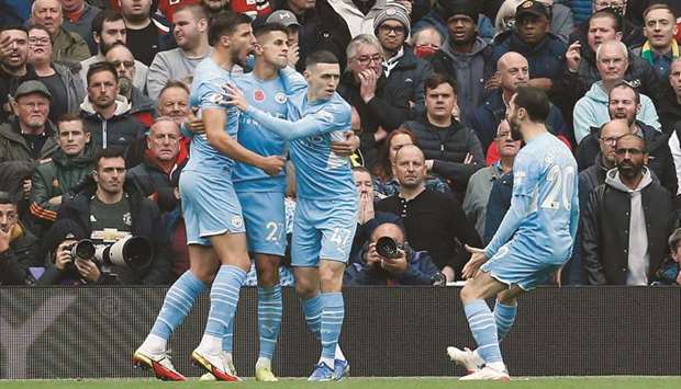 From left; Manchester Cityu2019s Ruben Dias, Joao Cancelo, Phil Foden and Bernardo Silva celebrate after Manchester Unitedu2019s Eric Bailly (not pictured) scored an own goal during the Premier League match at Old Trafford yesterday. (Reuters)