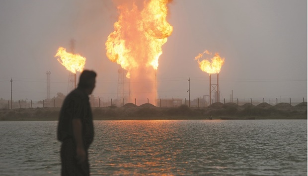 A man looks at flames rising from oil refinery pipes in Basra (file). Iraq plans to boost its oil-output capacity and entice global companies to work in the country.