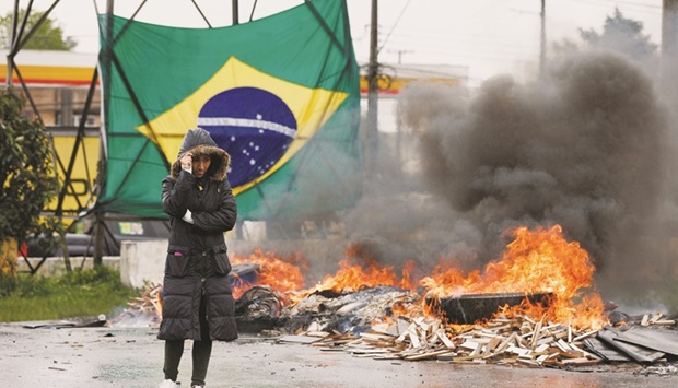 A person stands on a road next to a burning tyre as supporters of Brazilian President Jair Bolsonaro, mainly truck drivers, block a highway during a protest over Bolsonarou2019s defeat in the presidential run-off election, in Curitiba, in the state of Parana yesterday. (Reuters)