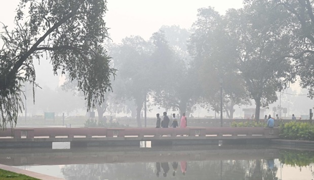 Pedestrians walk along a road near the India Gate amid heavy smog in New Delhi (AFP)