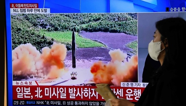 A woman walks past a television screen showing a news broadcast with file footage of a North Korean missile test (AFP)