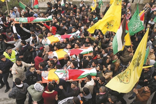 Mourners carry the bodies of four Palestinians, who were killed by Israeli security forces in the southern West Bank, during their funeral in the West Bank village of Sair on Friday.