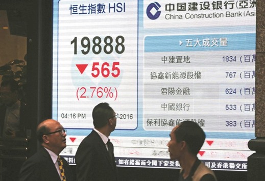 Pedestrians walk past an electronic sign showing the Hang Seng Index in Hong Kong. The exchange began the week sharply lower yesterday, slipping 2.8%, or 565.21 points, to close at 19,888.50 as bourses in China plummeted again.
