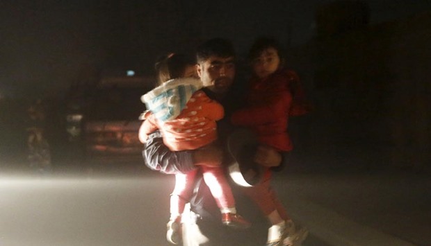 A man carries his children to a safe area from the site of an explosion in Kabul on Friday.