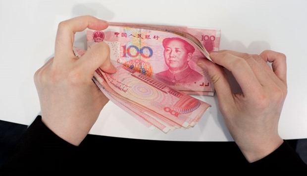 A Standard Chartered employee counts yuan banknotes at one of the banku2019s branches in Hong Kong. The Chinese currency tumbled 4.5% in 2015 to close at 6.4936 a dollar in Shanghai on December 31.